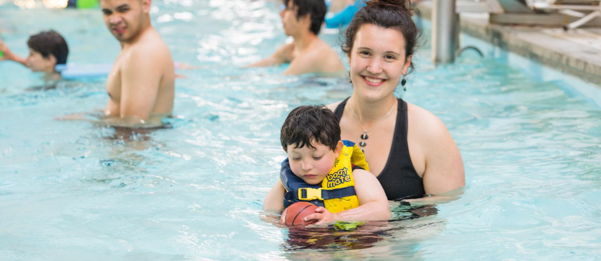 people in a pool and one woman holding a child