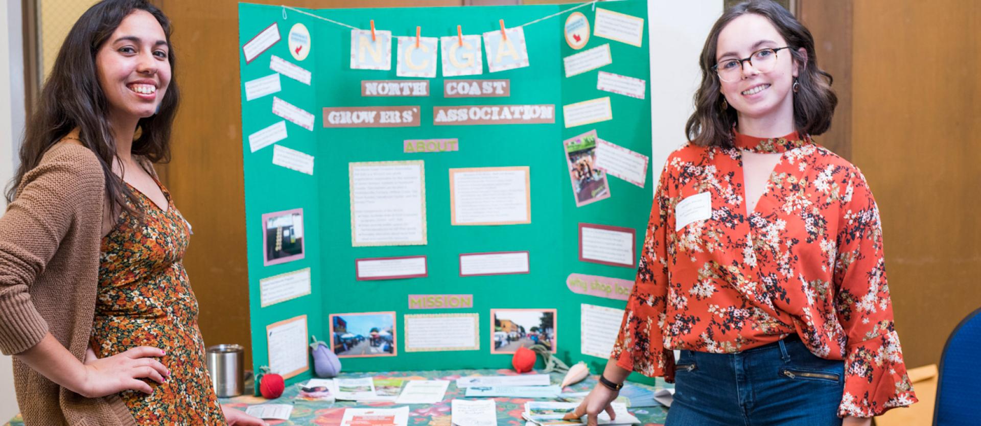 two students standing in front a poster board presentation