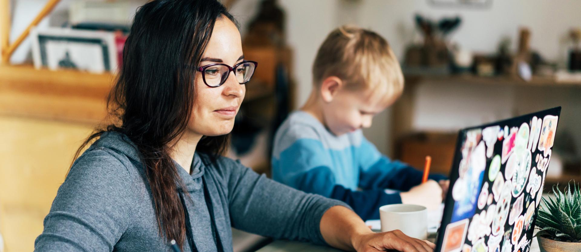 mom on her laptop with a kid sitting next to her