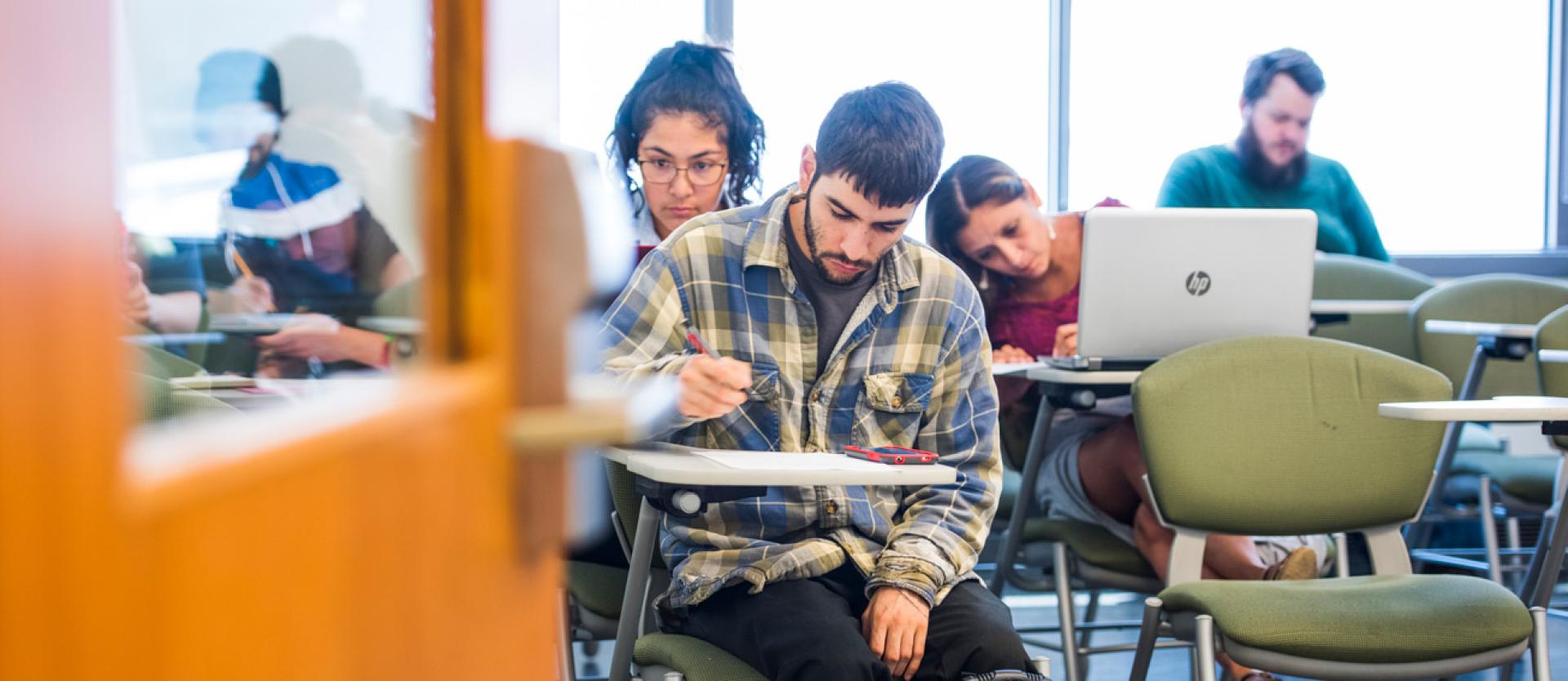 a student at a desk with other student in the background