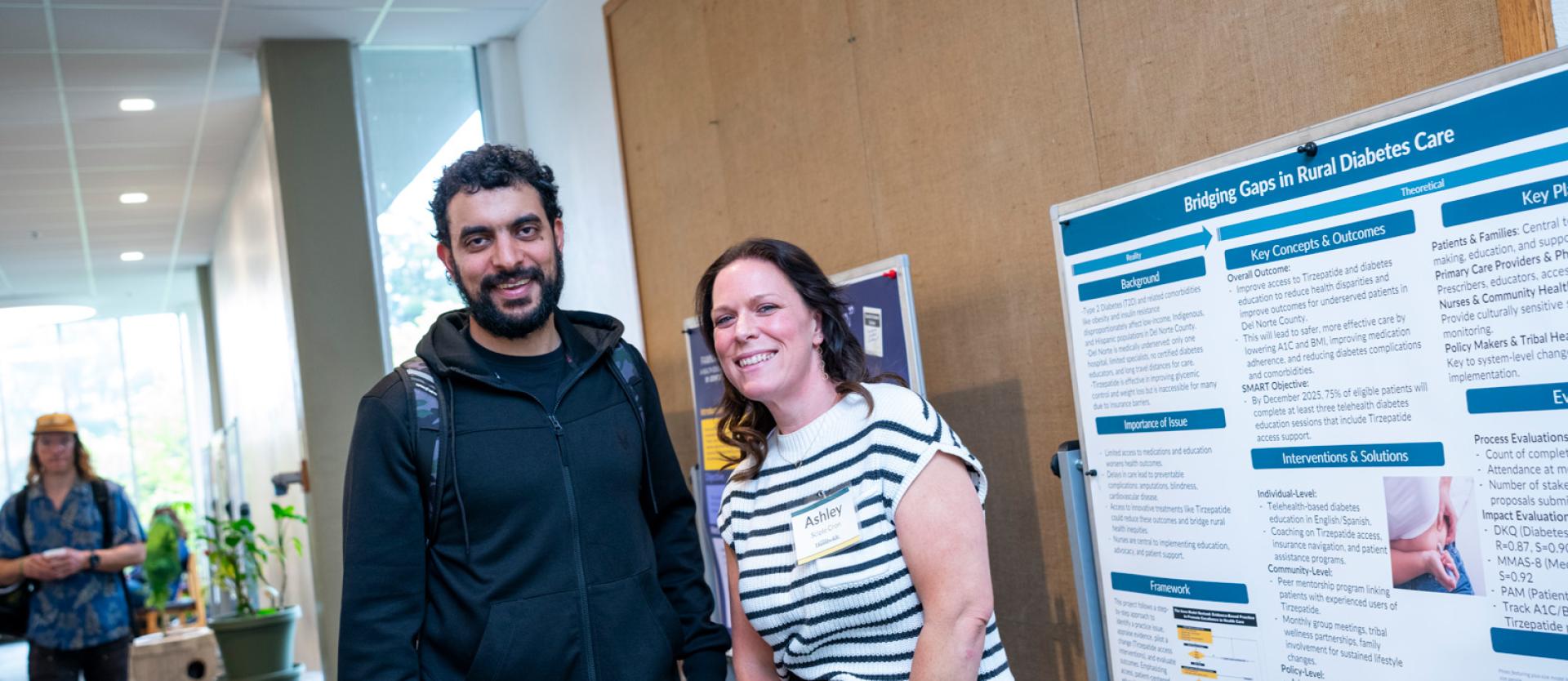 Two students standing next to a poster about Bridging the gap in rural diabetes care