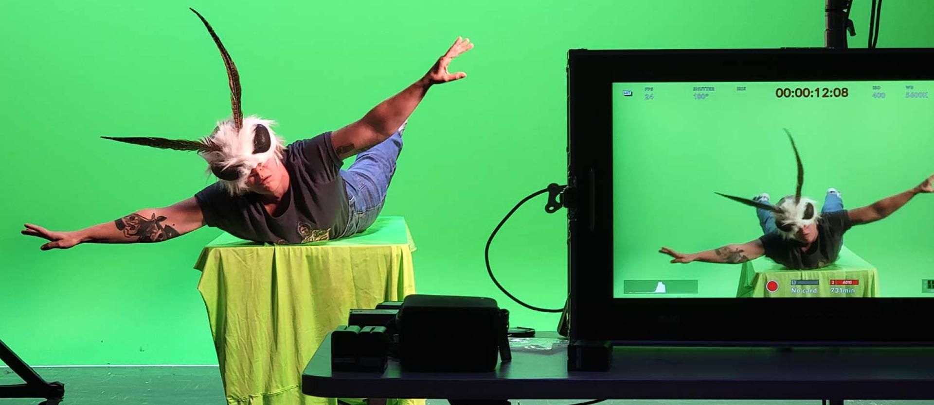 Actor on a table in front of a green screen