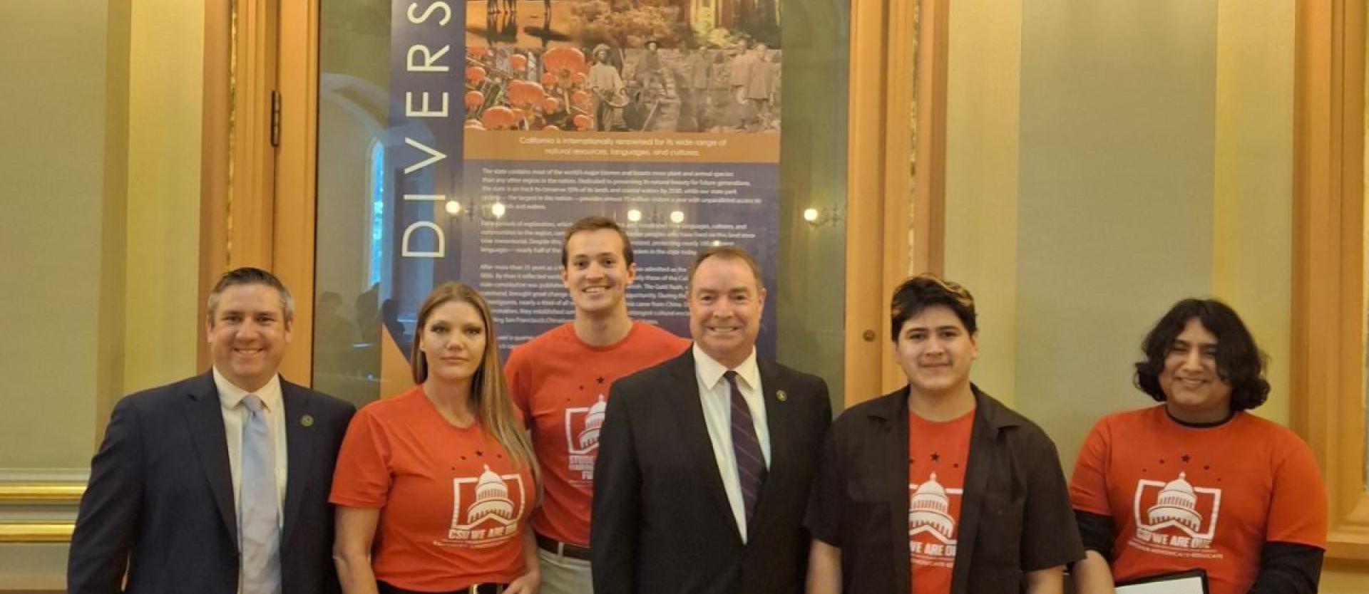 Four students wearing red meet with two California legislators