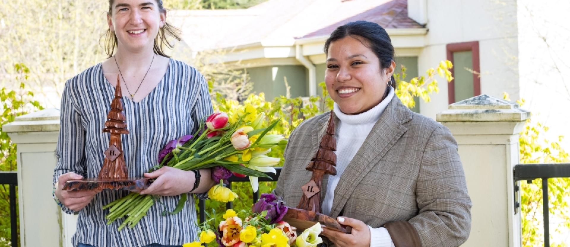 two students dressed formally holding flowers
