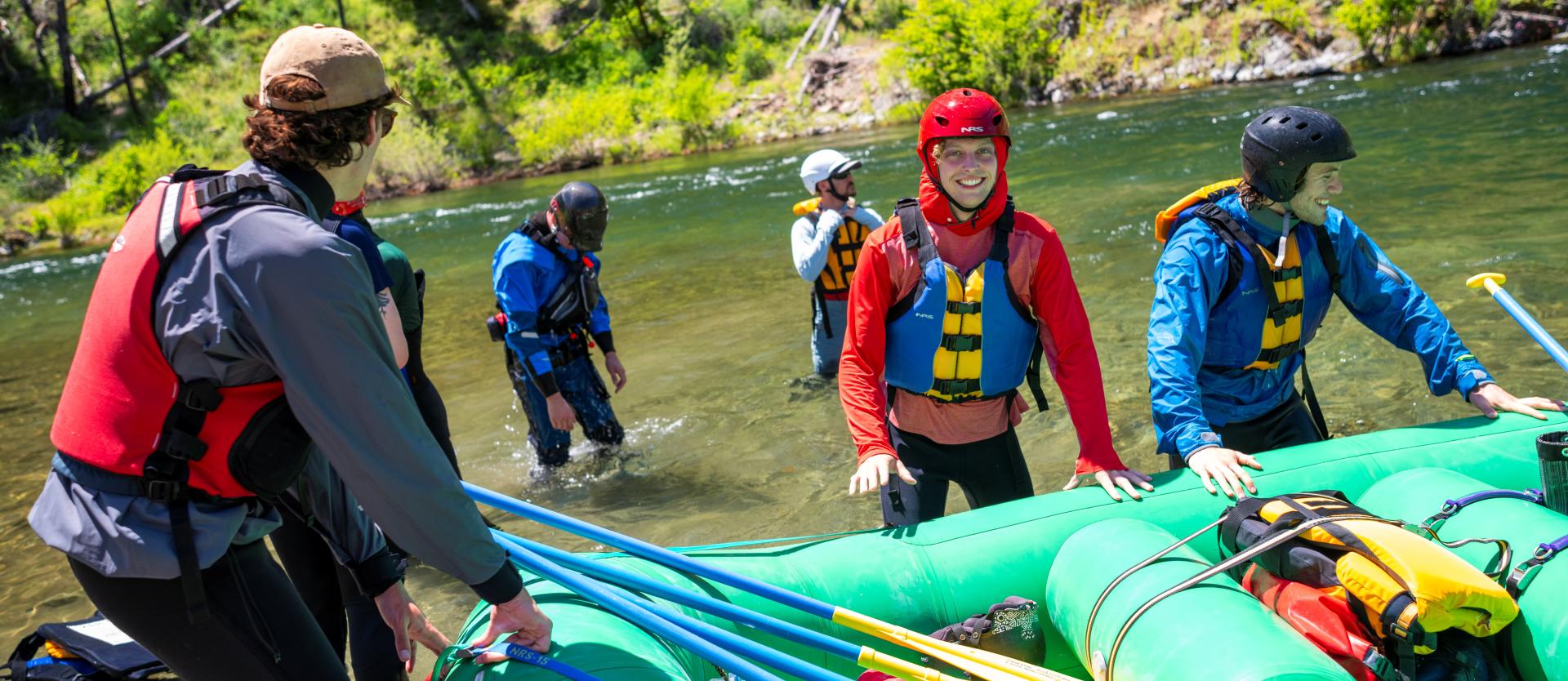 Students standing around a whitewater raft. 