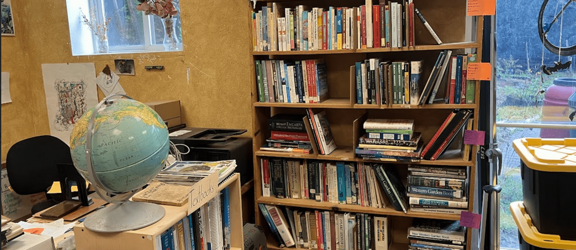 A bookshelf between a desk and glass doors in the CCAT Library.