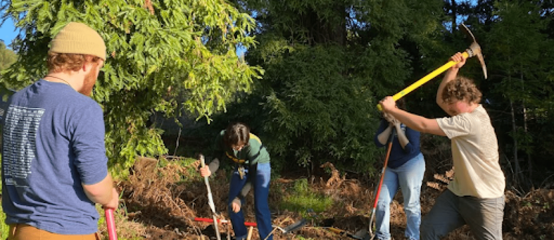 Image of 4 FSL Volunteers helping flatten an area in the FSL garden to create paths and garden beds.