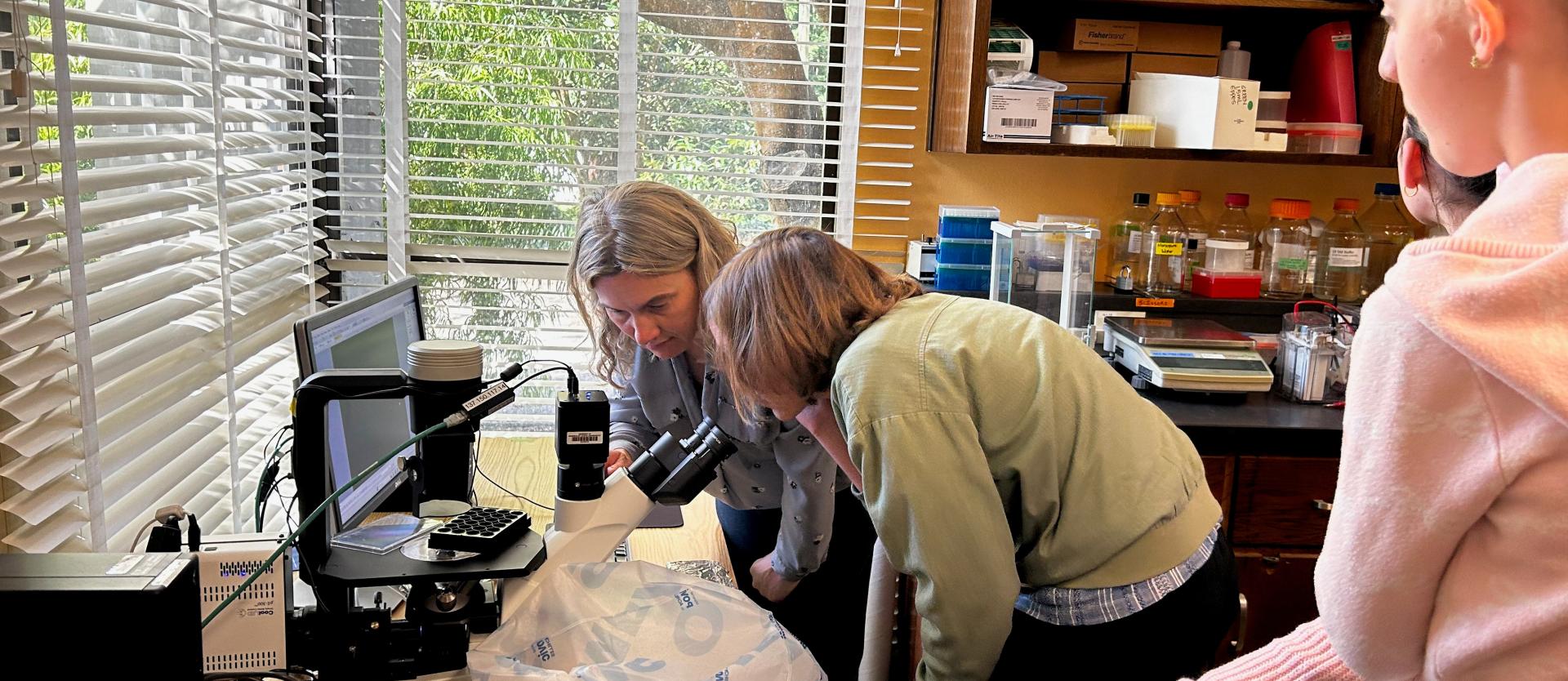 Amy & students looing through microscope