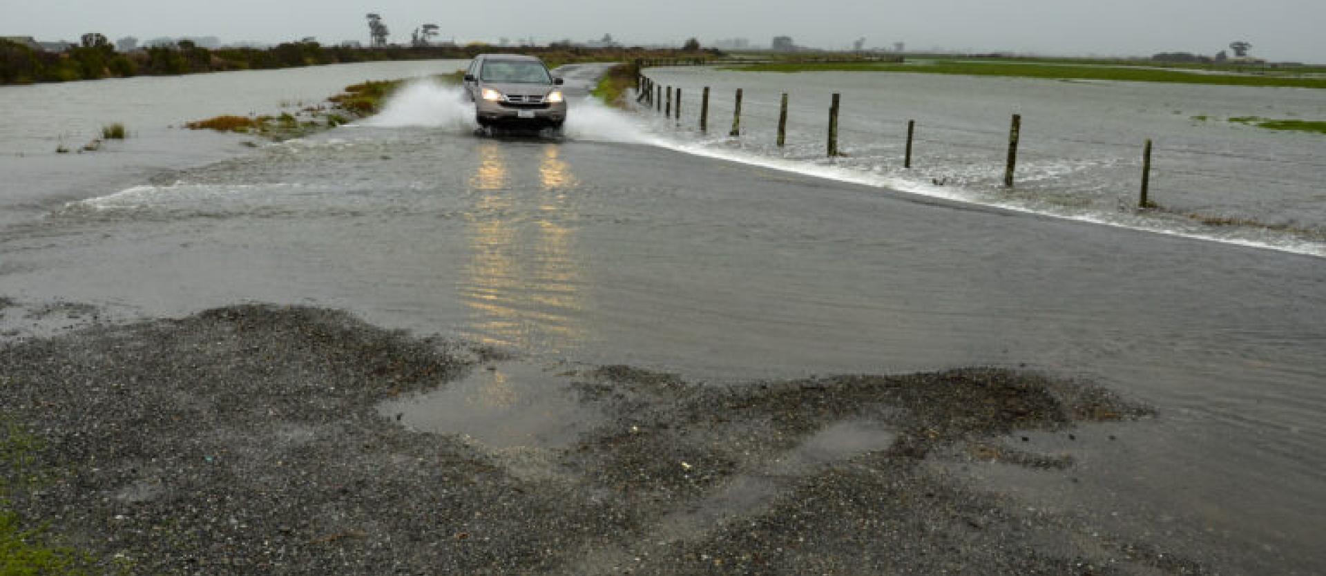 image of a car driving through a flooded section of a road
