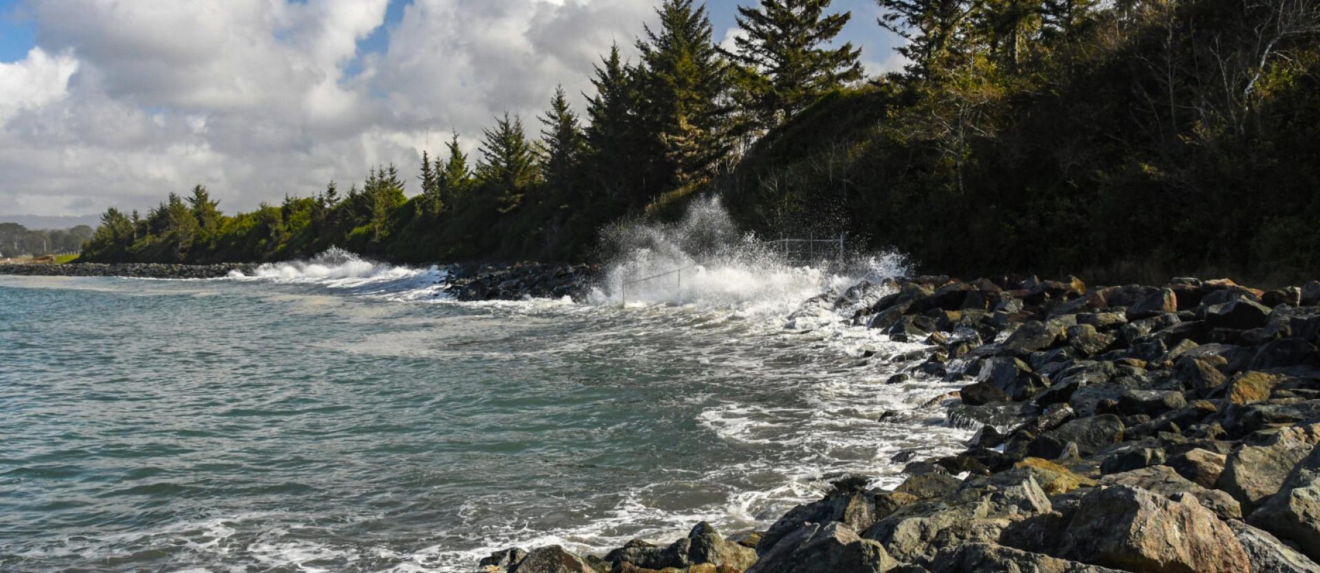 image of waves crashing against rocky rip rap at a beach
