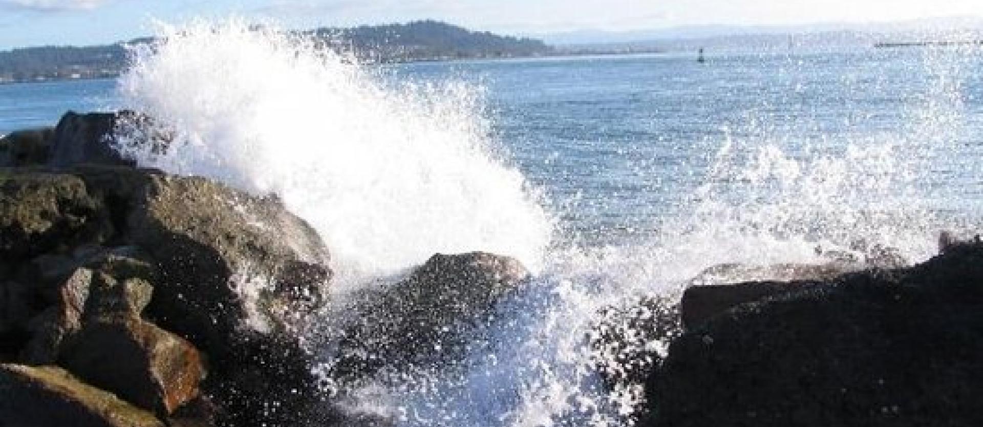 image of waves breaking over rip rap covered shoreline