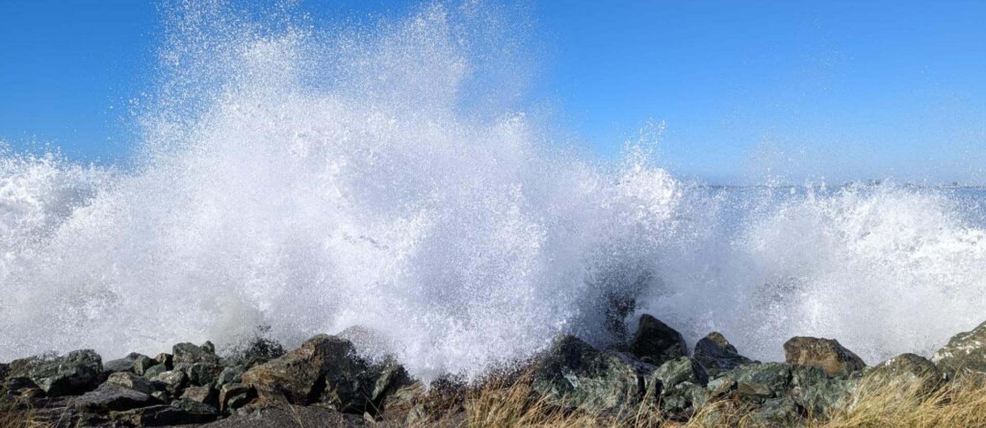 image of waves breaking dramatically over a rip rap covered shoreline