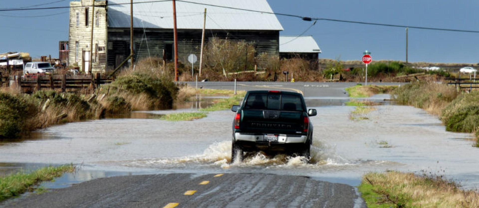 Image of a truck driving through a flooded section of road