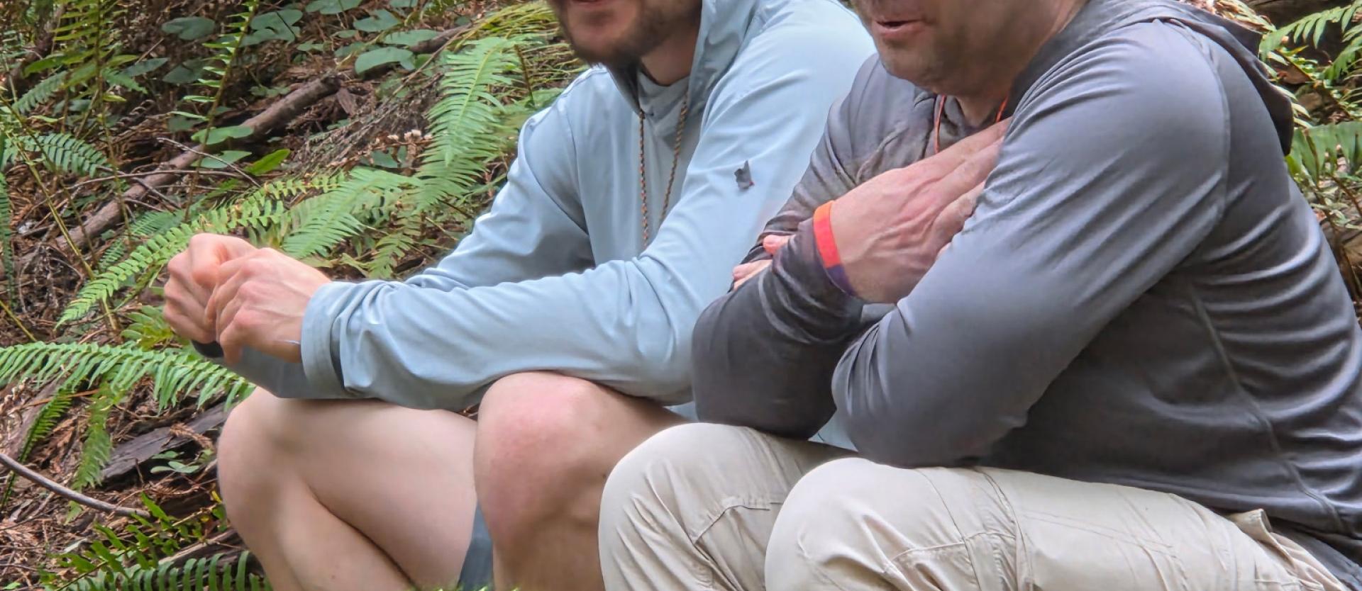 Two Hikers sitting on a log sharing some some smiles and laughter.