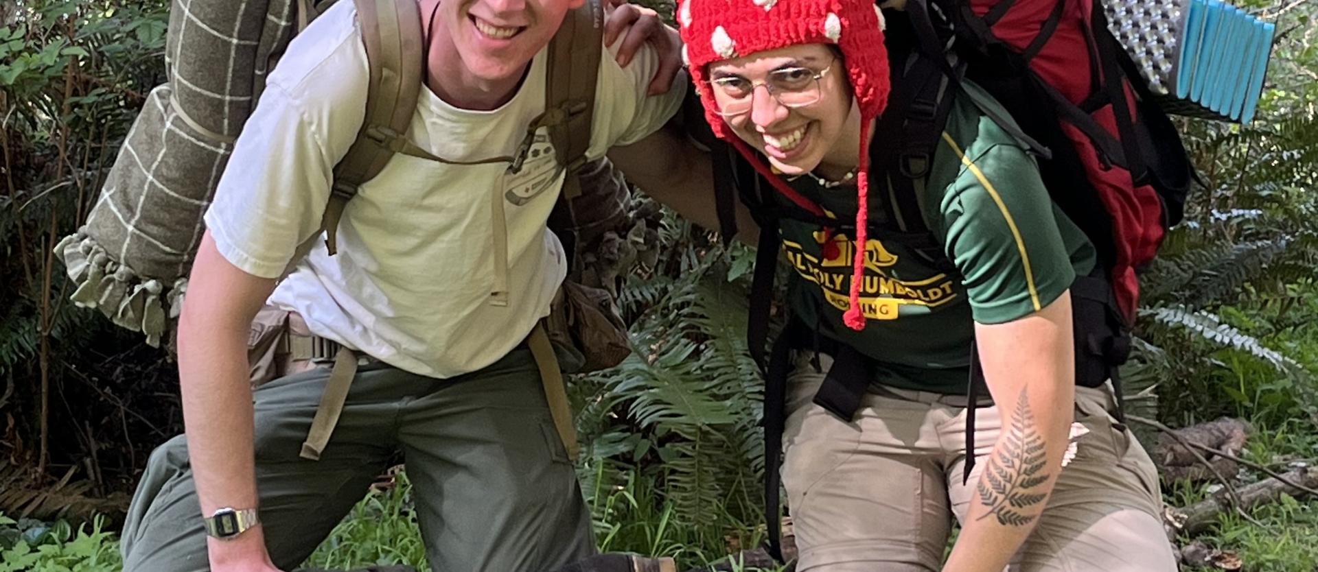 A couple of backpackers doing a goofy, mirrored stretch.