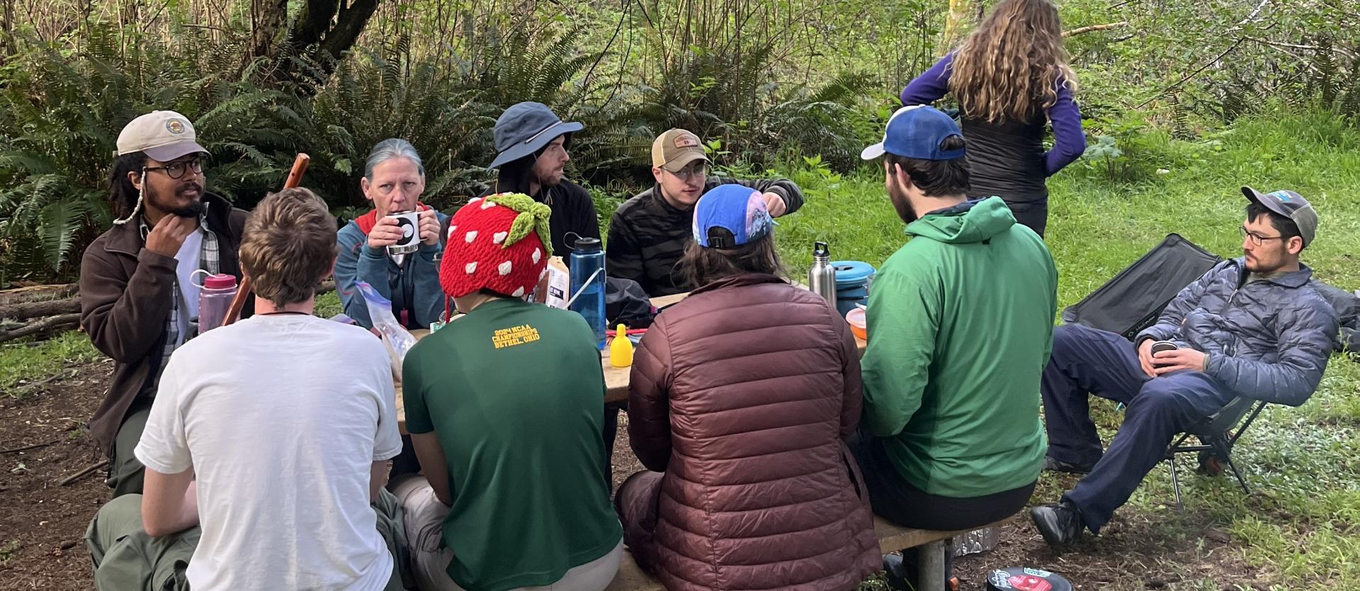 Backpacking group relaxing at a picnic table.