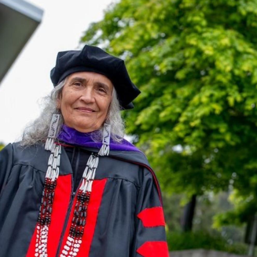 Professor standing outside wearing commencement robe