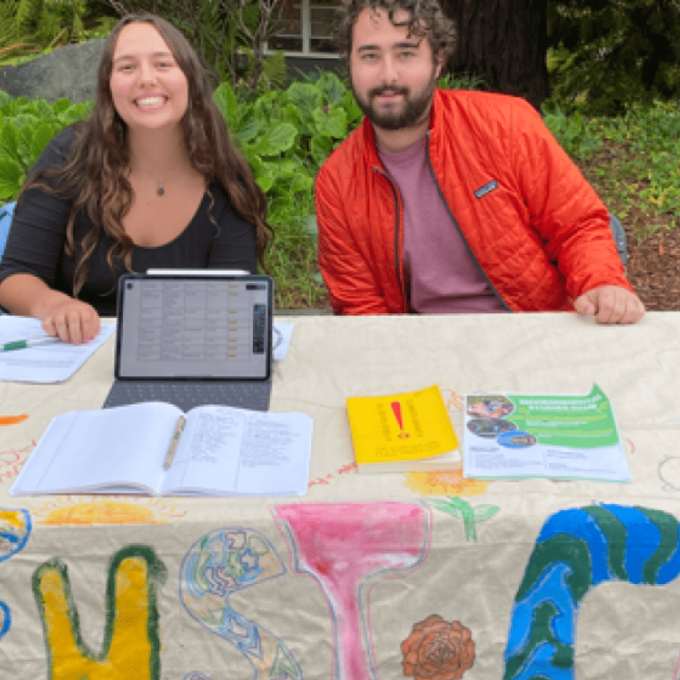two students at a table, one wearing a red jacker