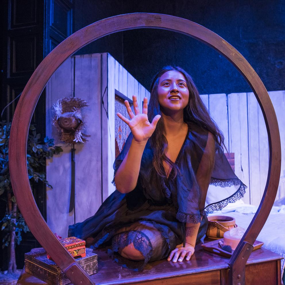 A woman inside a circular wood frame on stage