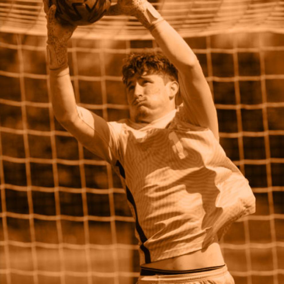 Soccer goalie catching the ball in front of the net