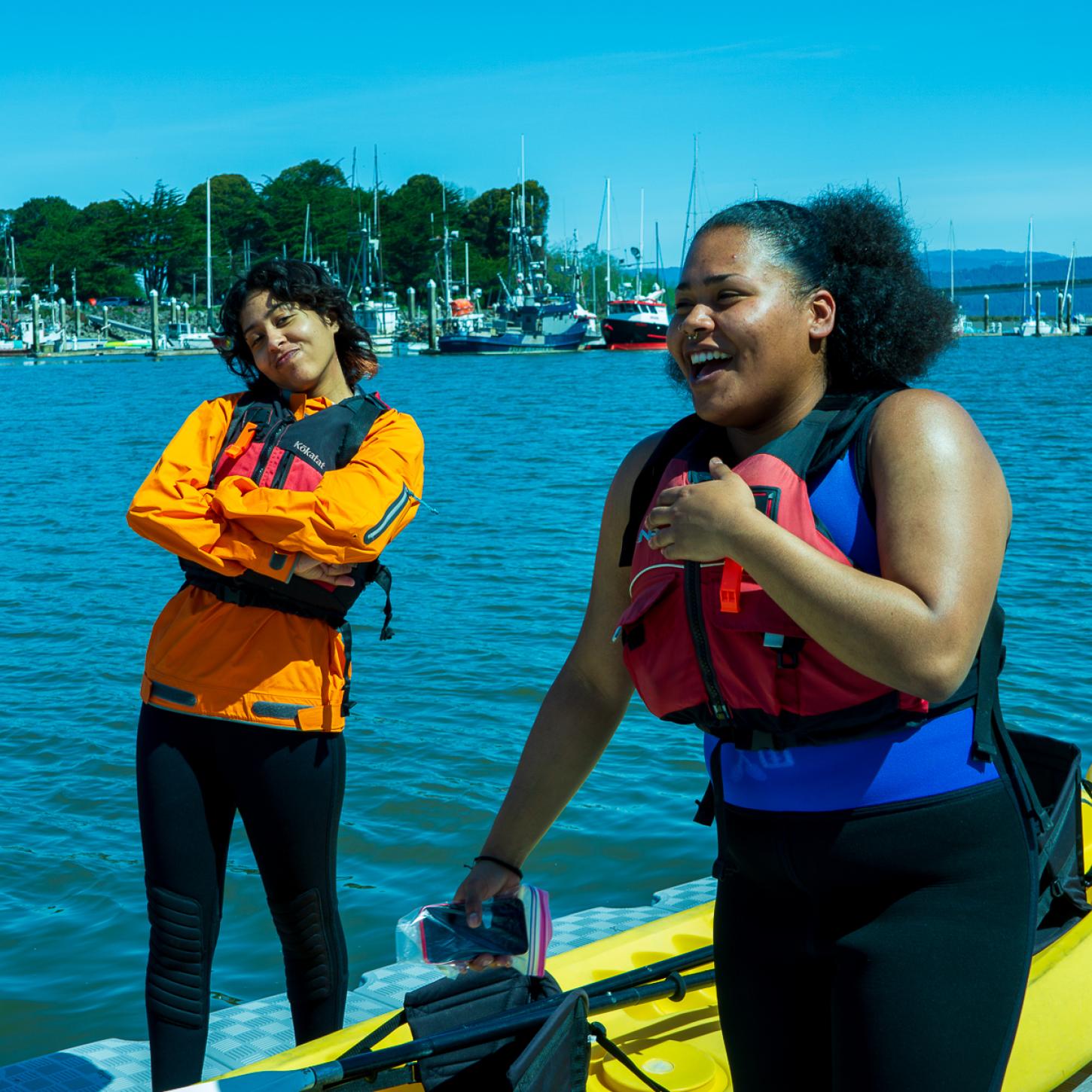 Two student pose and smile before paddling on Humboldt Bay