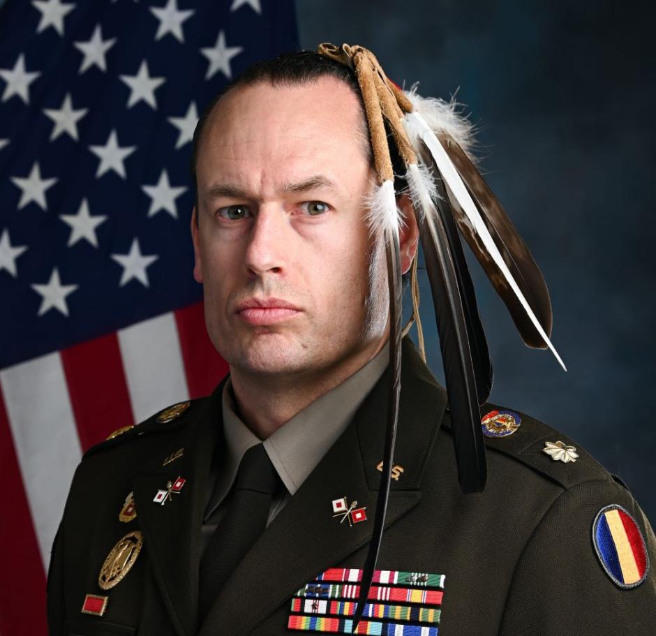 A portrait of Maj. Patrick Sorensen wearing his Native American regalia of feathers while wearing his U.S. Army uniform. 
