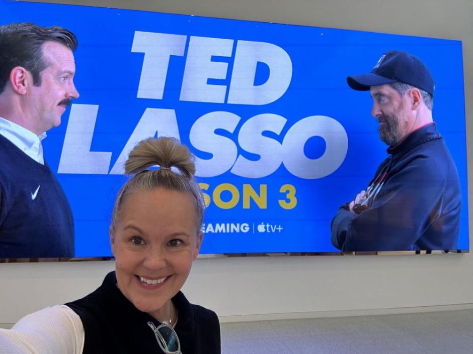 A photo of Leesa Coble in front of a poster for Ted Lasso A photo of Leesa Coble in front of a poster for Ted Lasso