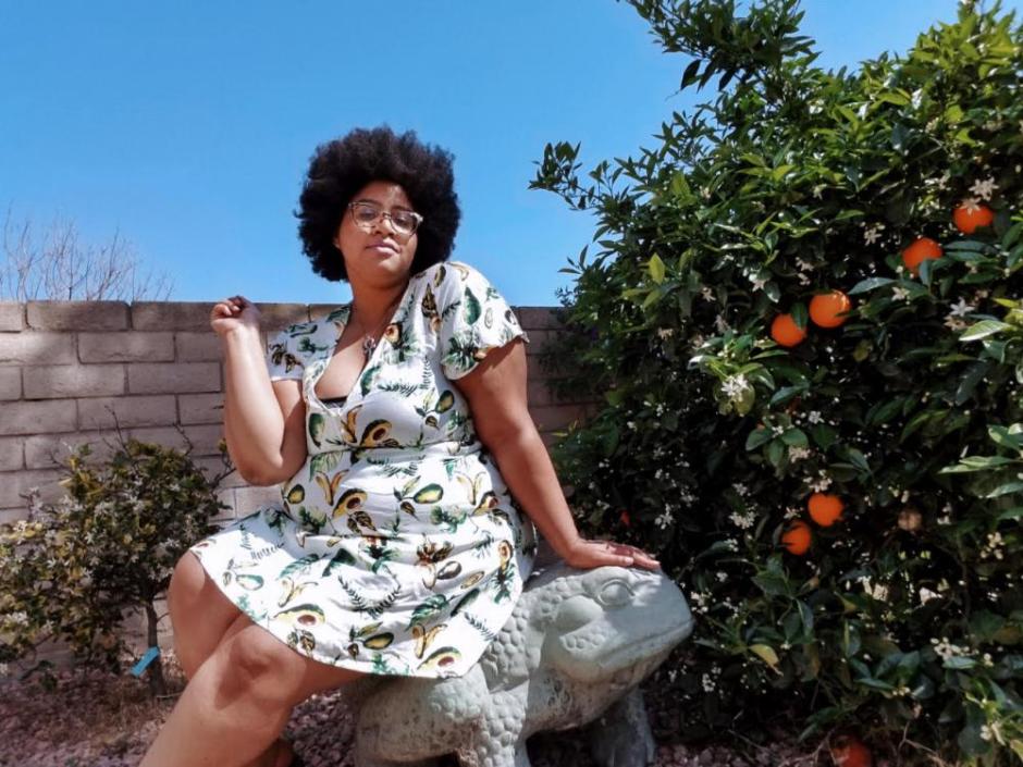 Sabina Gallier sitting next to a citrus tree wearing a dress. Sabina Gallier sitting next to a citrus tree wearing a dress.