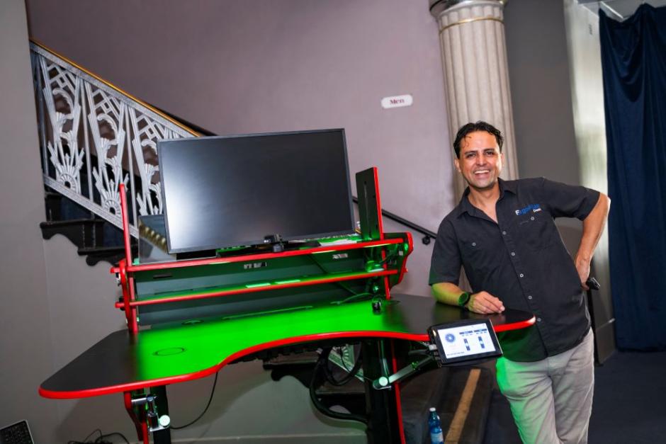 A photo of Vico Hernandez standing next to his innovative ErgoFlex Desk at regional commencement. A photo of Vico Hernandez standing next to his innovative ErgoFlex Desk at regional commencement.