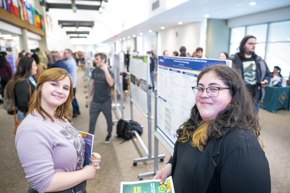2 female students smiling with ideaFest programs in their hands