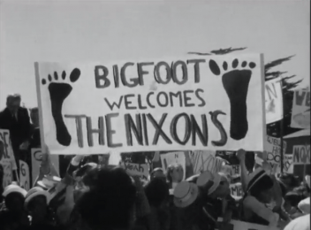 historic black and white photo of a crowd holding a banner that says Bigfoot welcomes the Nixons