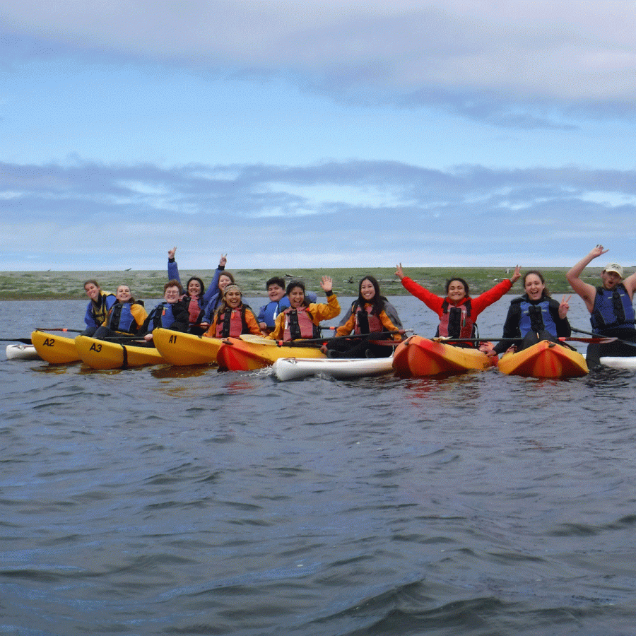 Large group of people in kayaks on a lagoon smiling