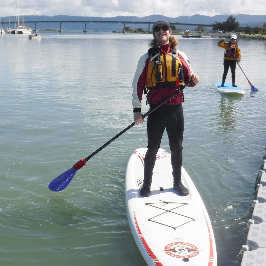 2 individuals on holding paddles on Stand Up Paddleboards in Humboldt Bay. 