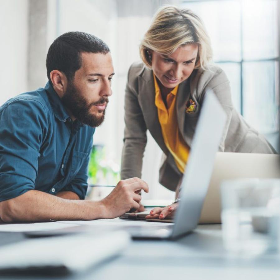 Man and woman discussing their work, with a computer