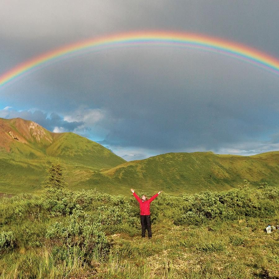 Rainbow above landscape with person on the ground
