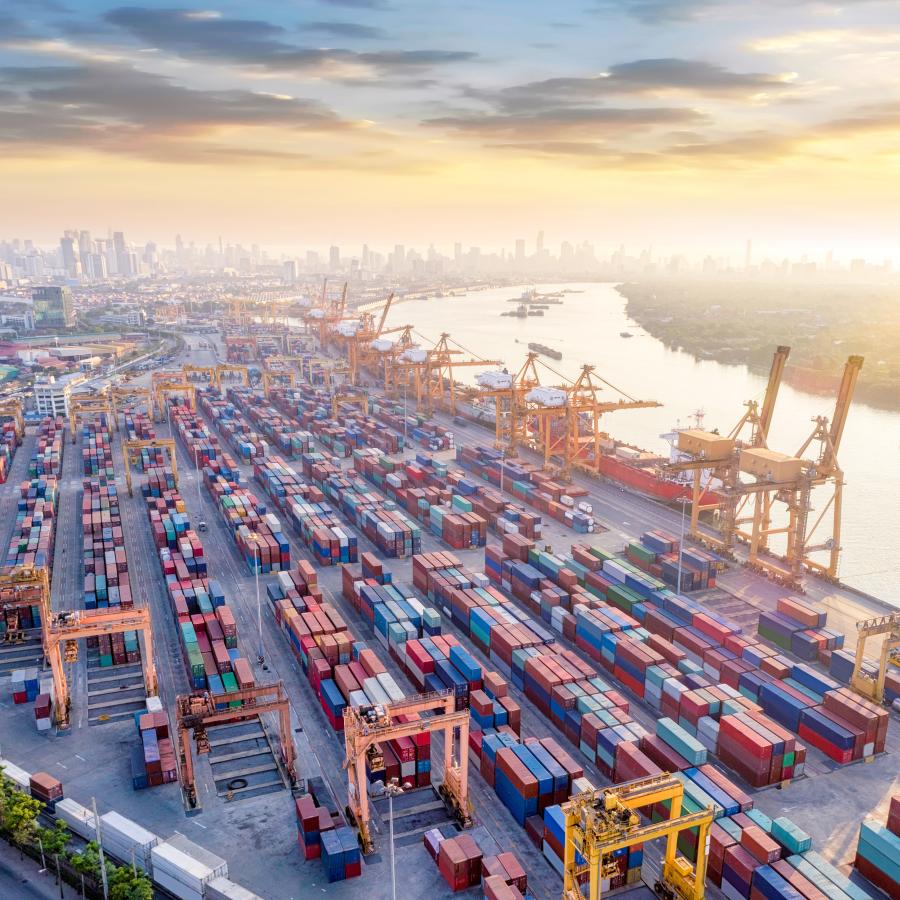 bustling commercial port terminal filled with hundreds of shipping containers and cranes, alongside a river