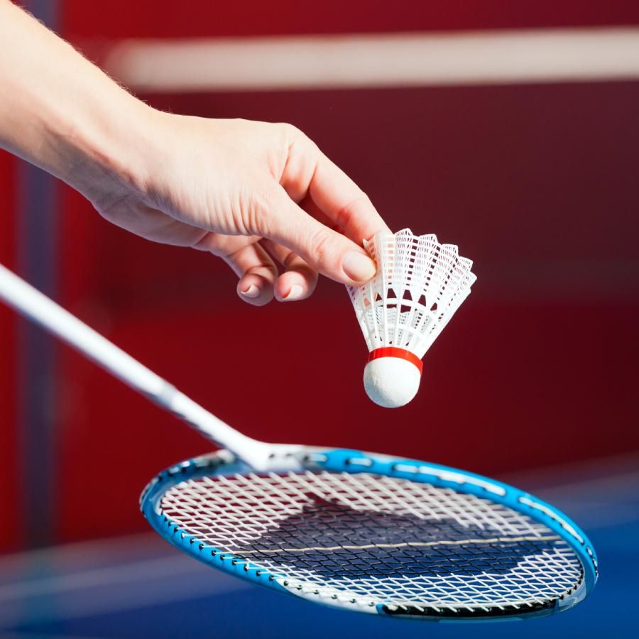 person serving the birdie with a badminton racket