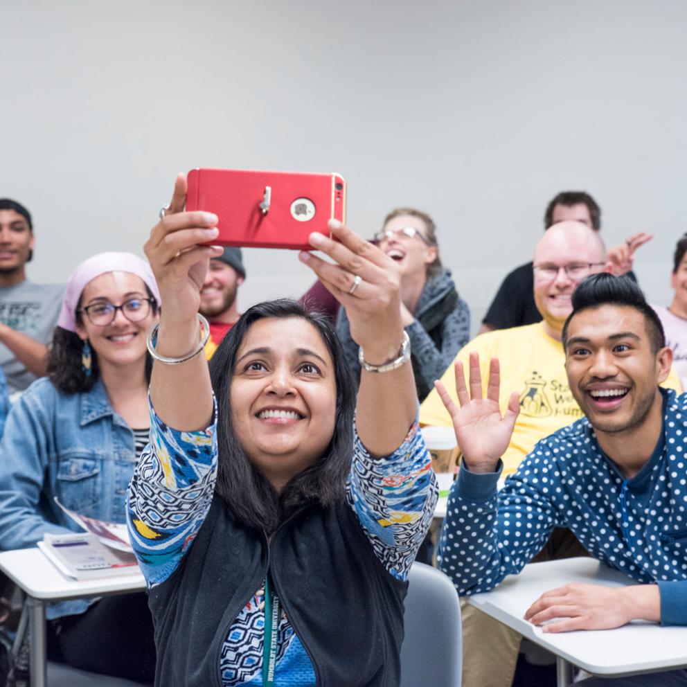 student with a phone camera taking a selfie of her and the clas