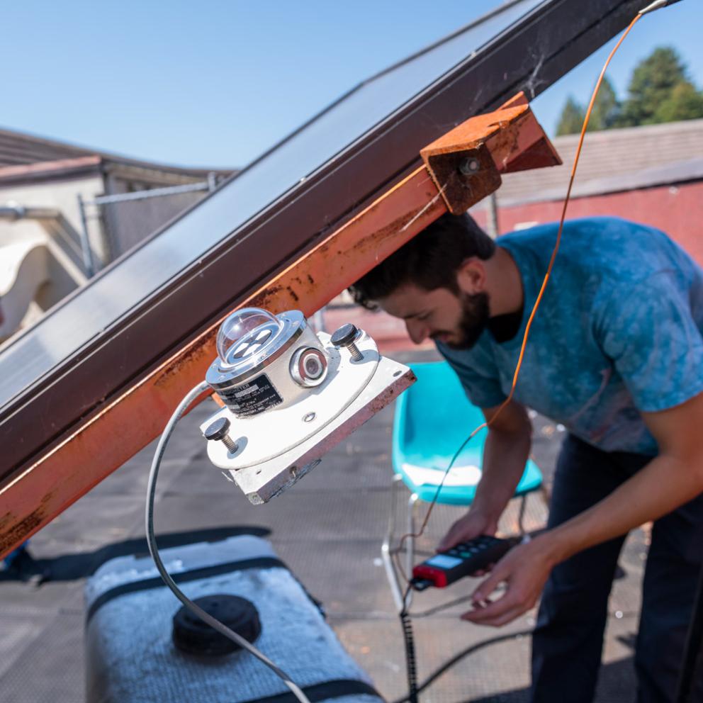 student outside under a solar array working on wires