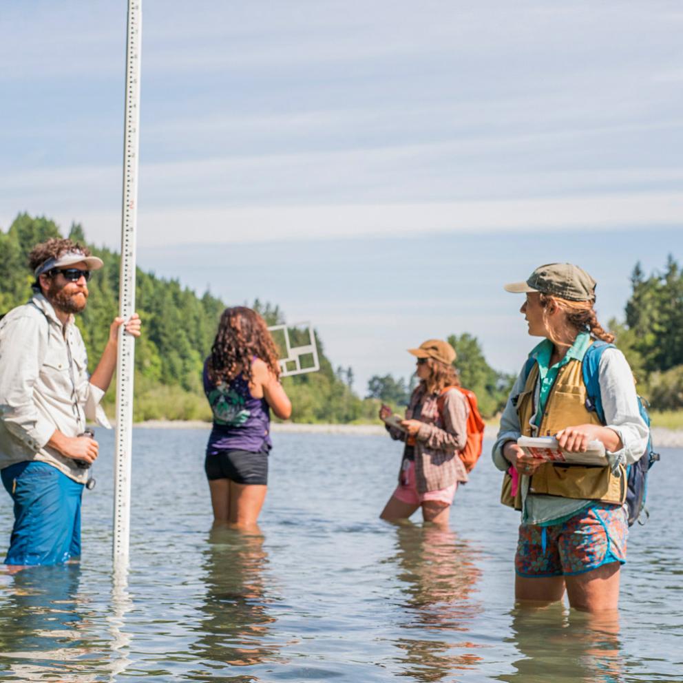 Students standing in the water with a measuring device