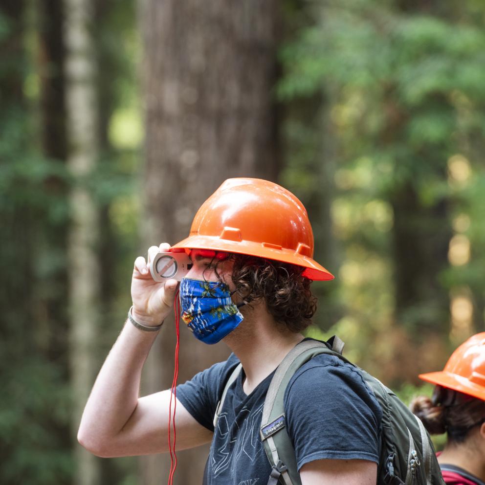 student in the forest looking through a scop