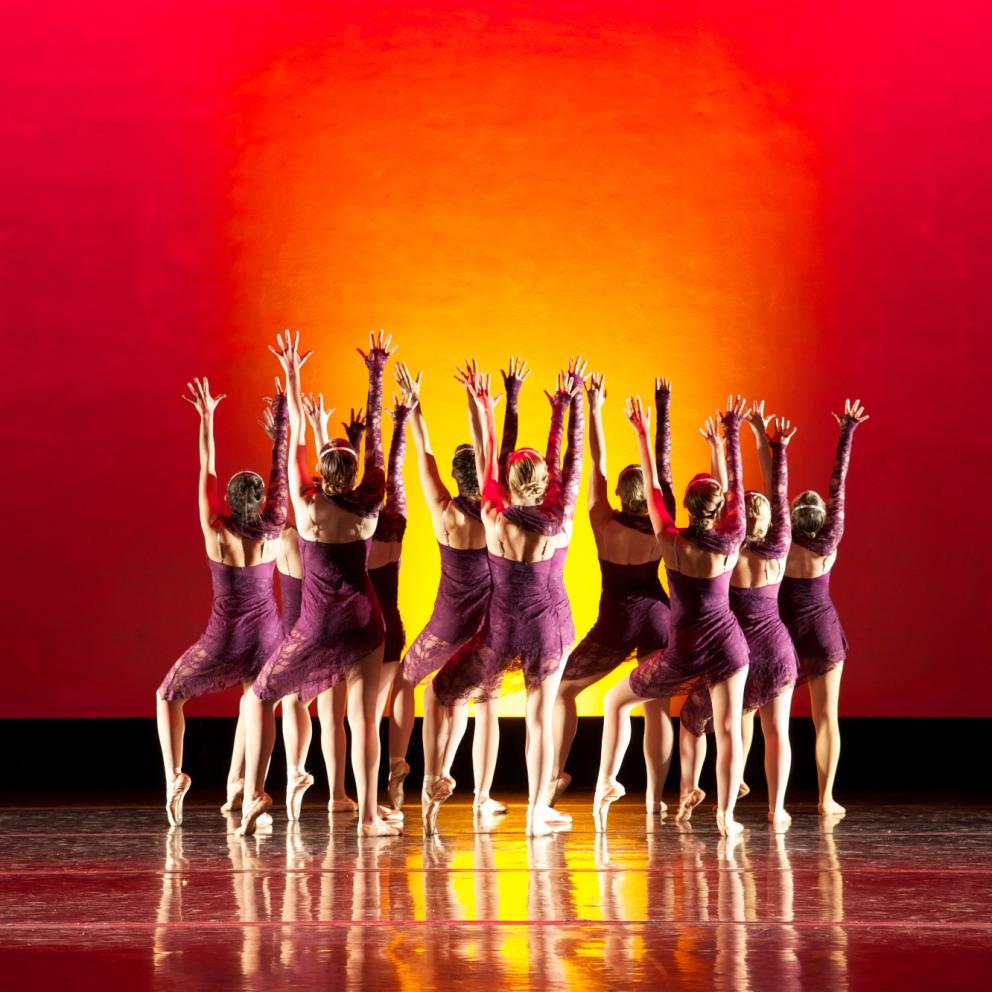 students facing each other in a circle performing with a red background