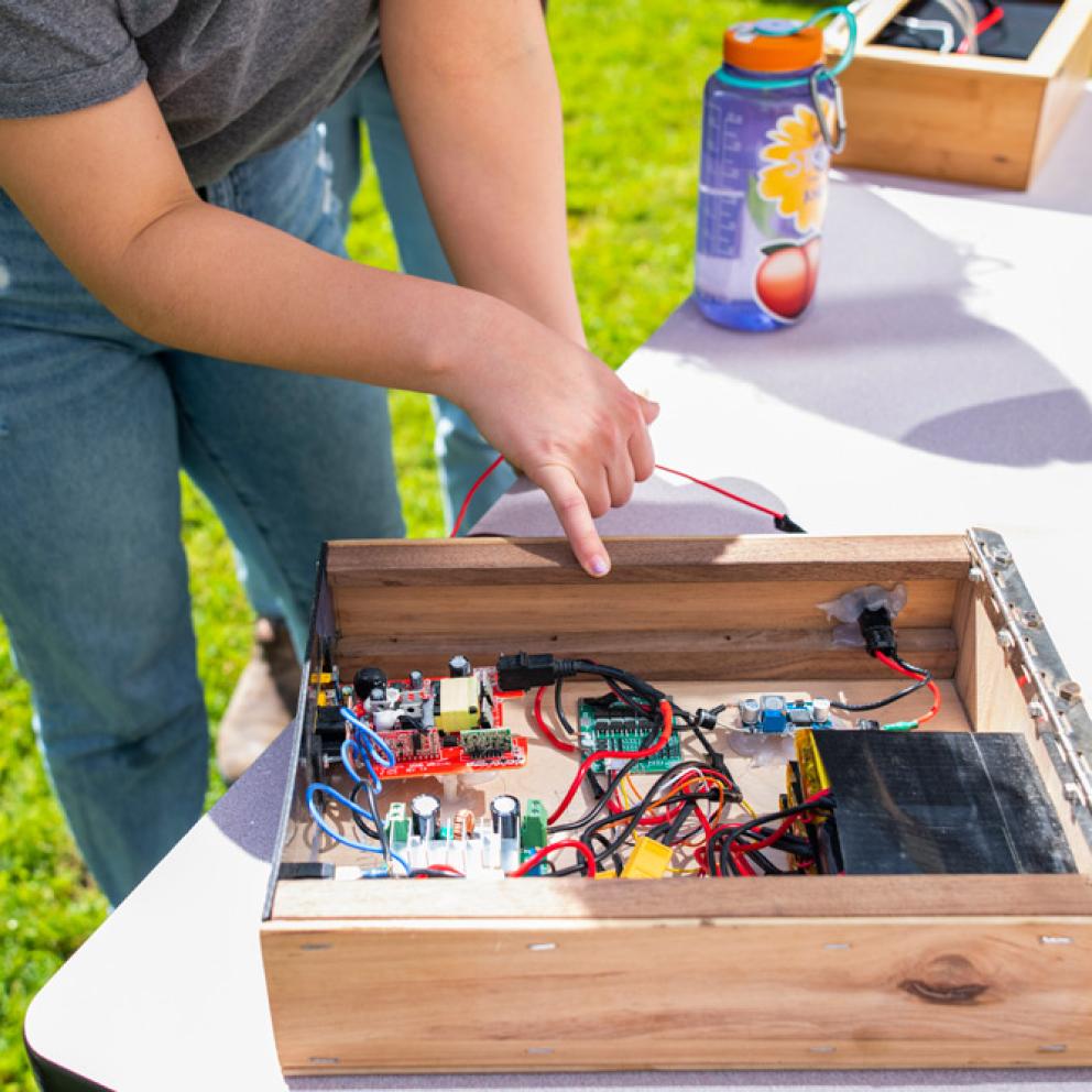 students looking at a table with a box and wires