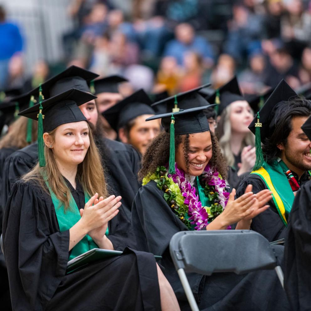 graduates at commencement smiling and clapping