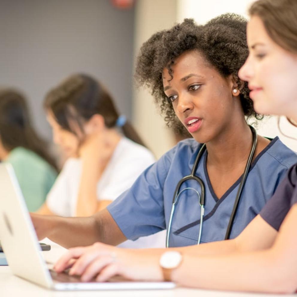 two nursing students looking at a laptop