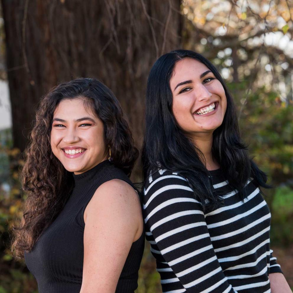 Students standing back to back in front of a tree