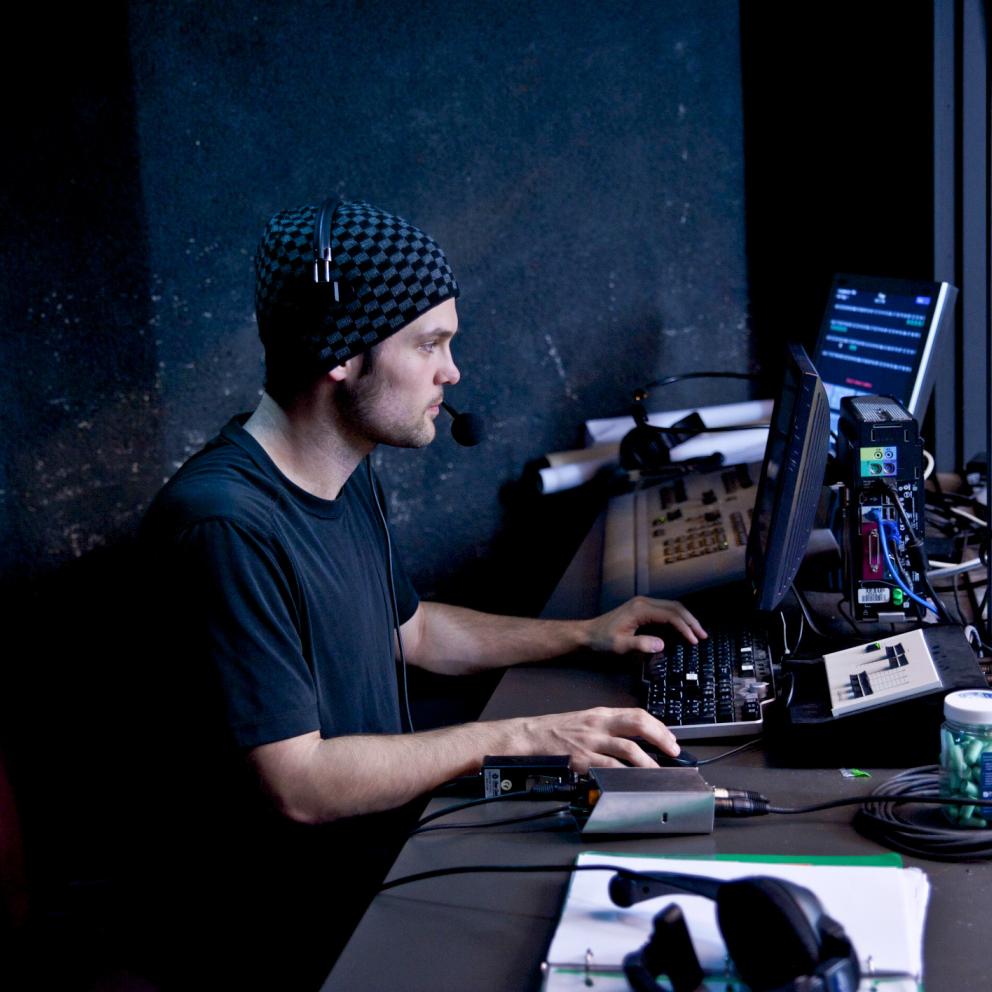 Student in sound booth running sound and lightning during a performance
