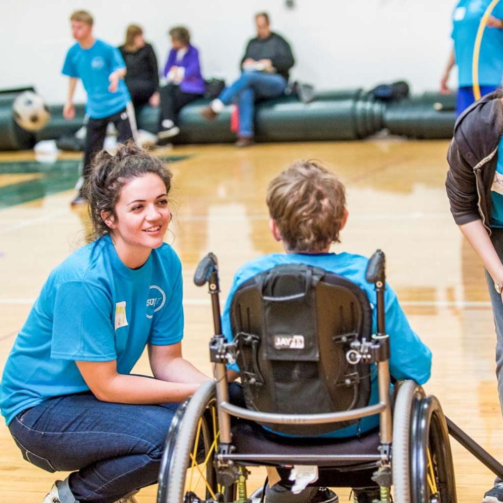young student in a wheel chair being helped by a student teacher