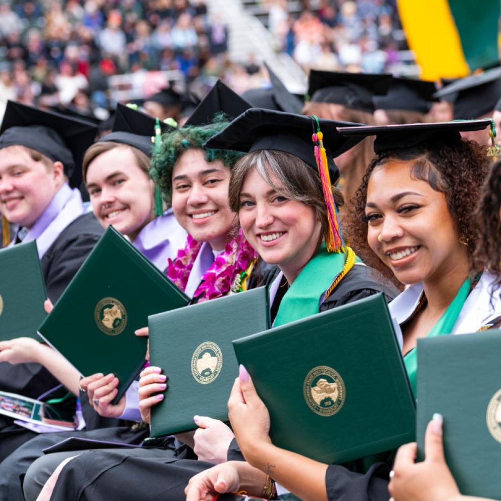 Graduates at commencement wearing caps and holding diplomas