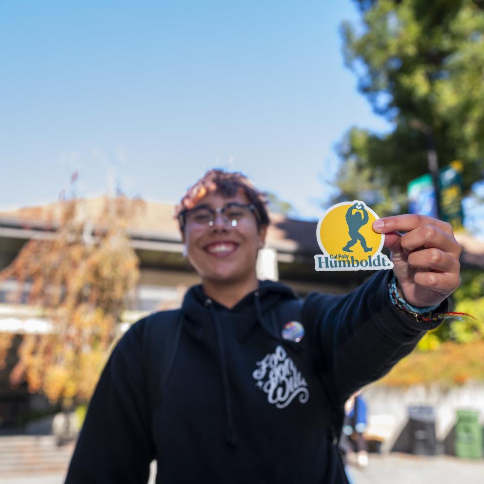 Student Holding Up Cal Poly Humboldt Sasquatch Sticker